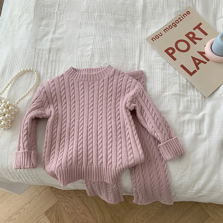 Pink cable-knit sweater and matching pants displayed flat