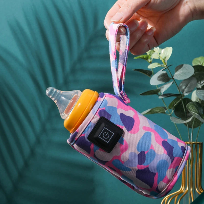 Hand carrying a pink camouflage bottle warmer by its fabric loop.