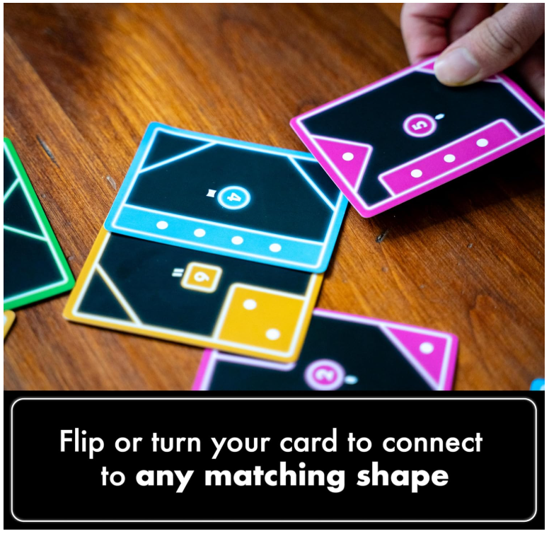 Hand positioning a pink shape card beside blue and yellow cards