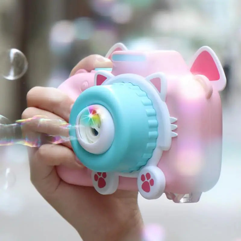 Side view of a pink cat-shaped bubble camera held in one hand while releasing bubbles.