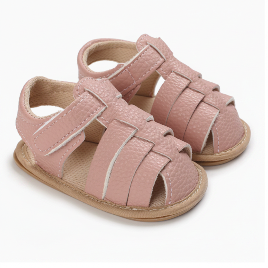 Pair of pink closed-toe baby sandals with interwoven straps and ankle fastenings