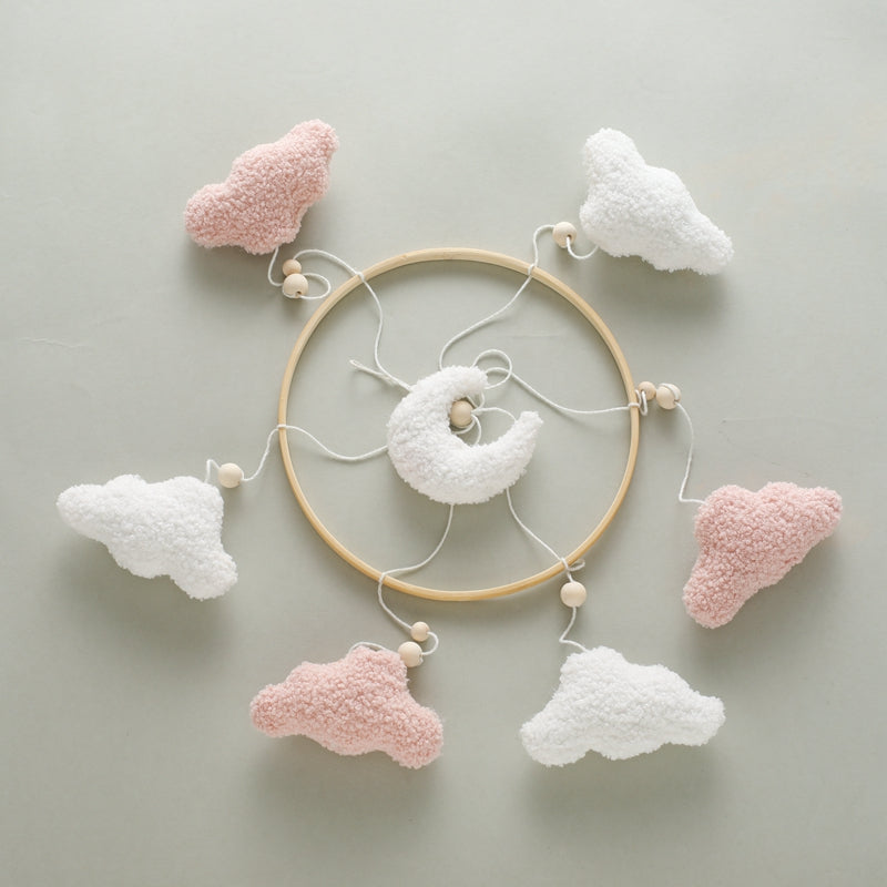 Pink cloud and moon mobile arranged flat to show the wooden ring, cords, and hanging shapes