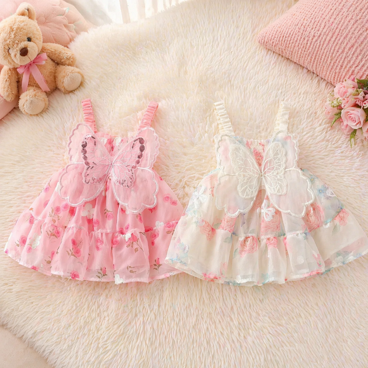 Pink and cream floral baby dresses with butterfly wings, laid flat side by side