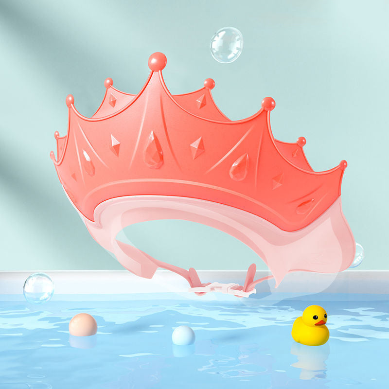 Pink crown-shaped bath visor with an adjustable band against a bubble-themed background