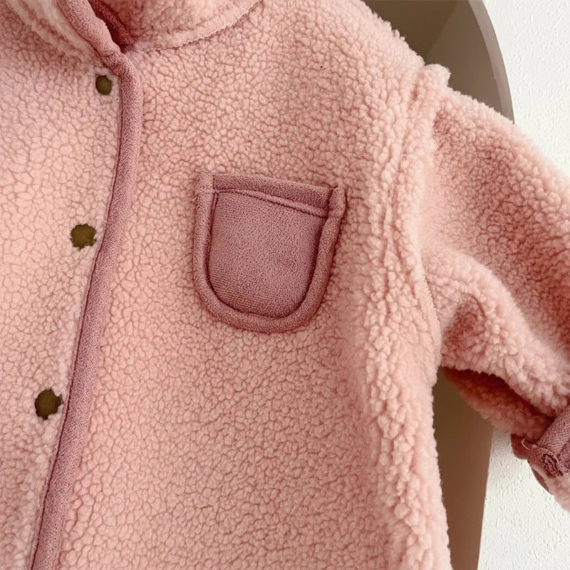 Close-up of pink fleece on a baby romper with a chest pocket and snap-button front