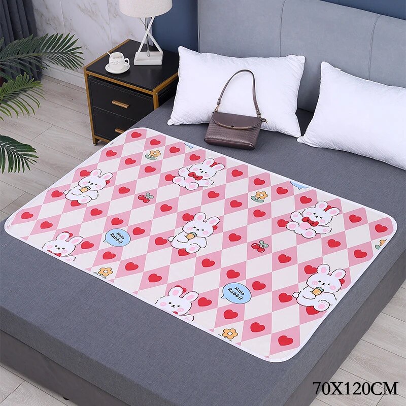 Pink heart-and-bunny changing mat on a gray bed, labeled 70 x 120 cm.