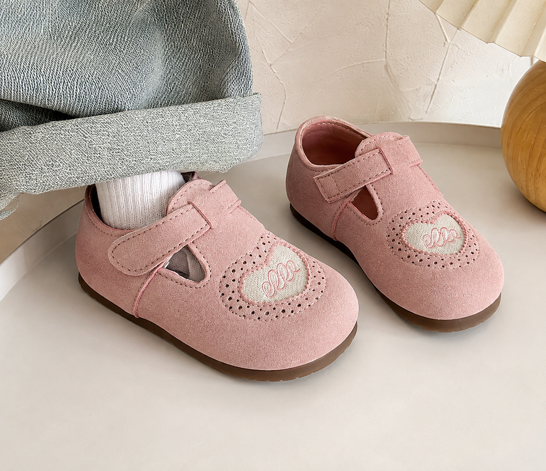 Pink heart-detail shoes with hook-and-loop straps beside a cuffed denim leg and white sock