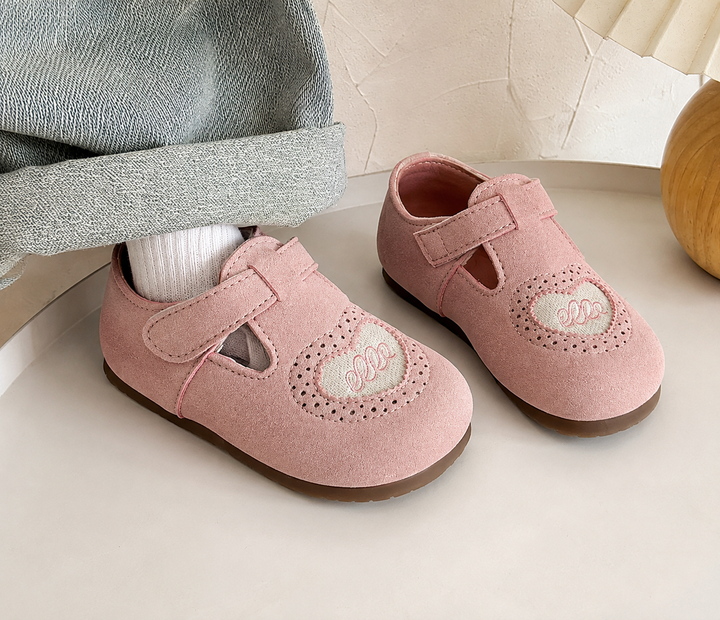 Pink heart-detail shoes with hook-and-loop straps beside a cuffed denim leg and white sock
