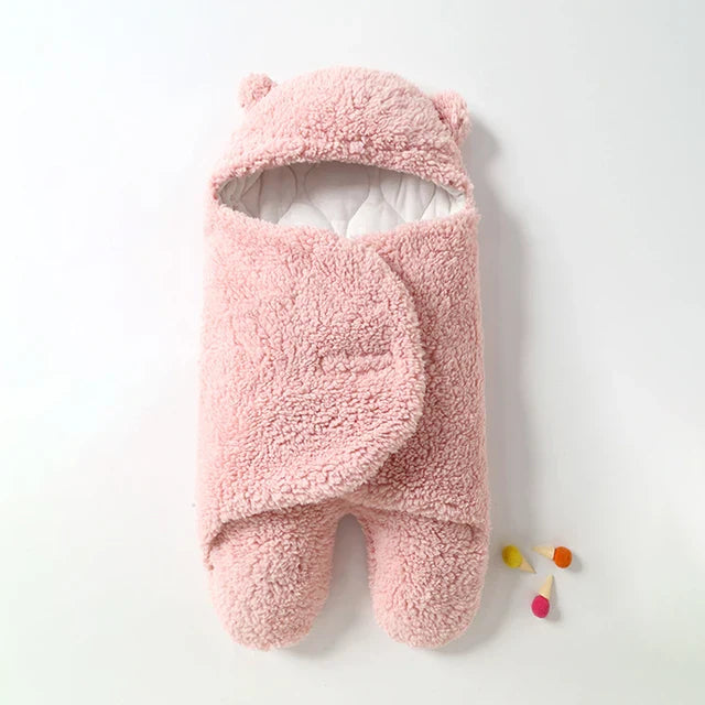 Pink hooded baby wrap blanket with white lining visible around the face opening.