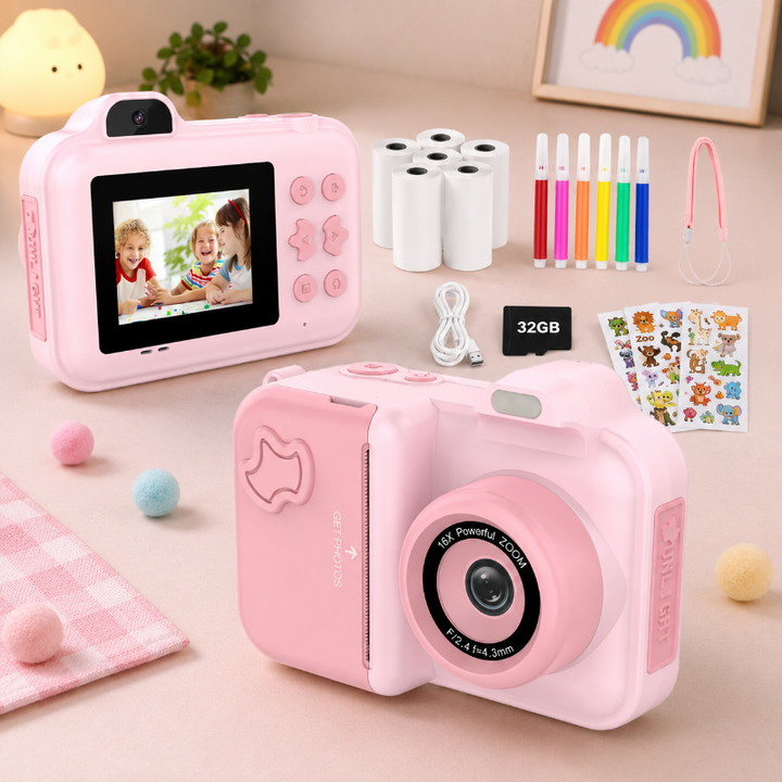 Pink instant-print camera kit with front and rear views, paper rolls, pens, stickers and a 32GB card