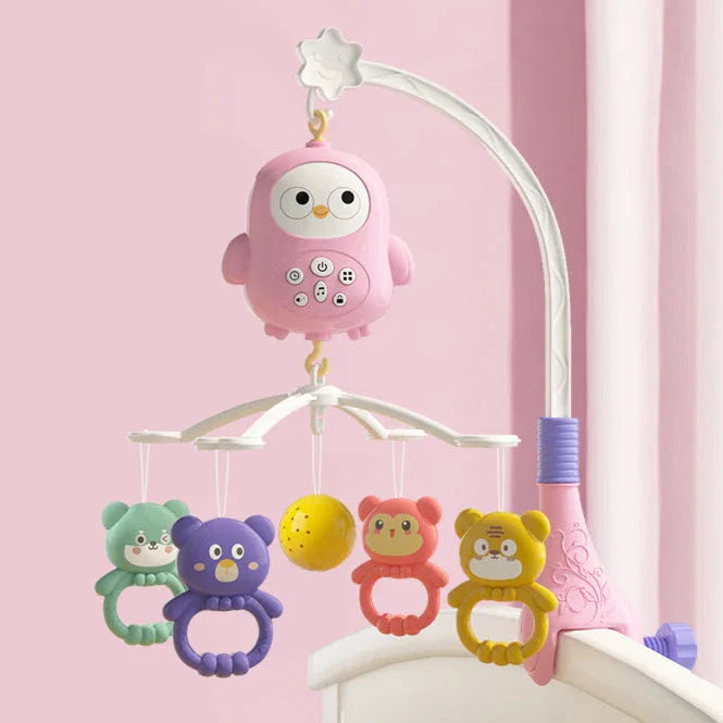 Pink owl crib mobile mounted on a crib rail with colorful animal-shaped hanging toys.