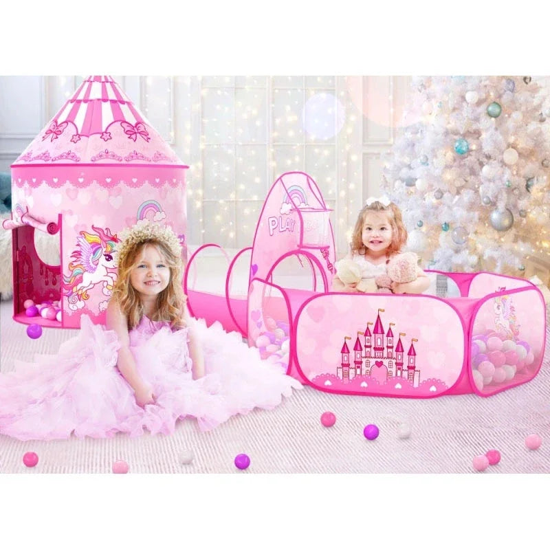 Two children beside a pink castle tent, tunnel and ball pit arranged indoors.