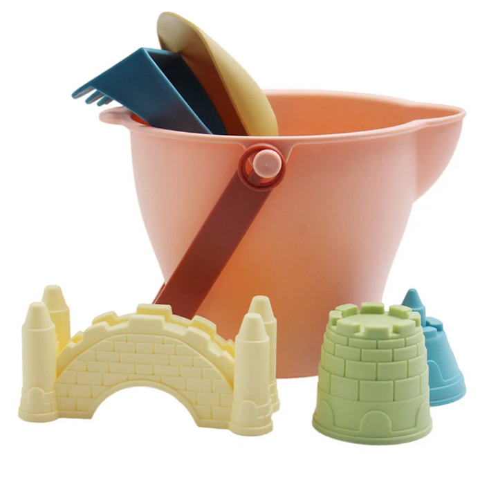 Pink pouring bucket with a yellow scoop, blue rake, and three colorful sand molds
