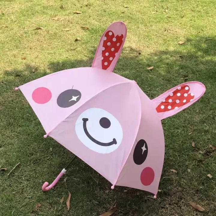 Pink rabbit umbrella with long raised ears and a smiling face, displayed on grass
