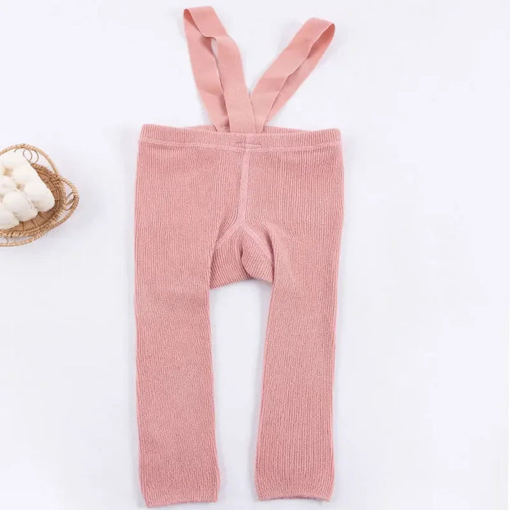 Pink ribbed baby leggings with matching suspenders laid flat