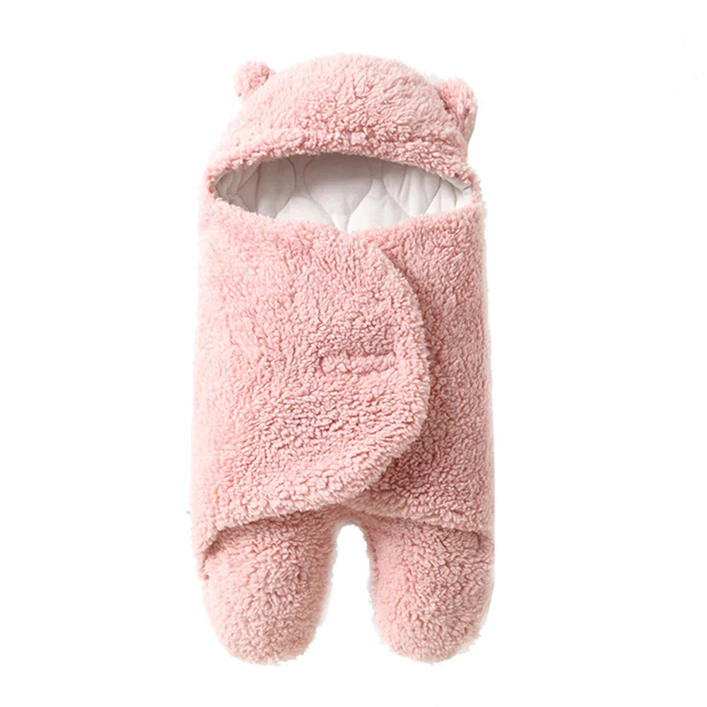 Pink baby wrap blanket with a textured sherpa exterior, bear-ear hood, and white quilted lining.