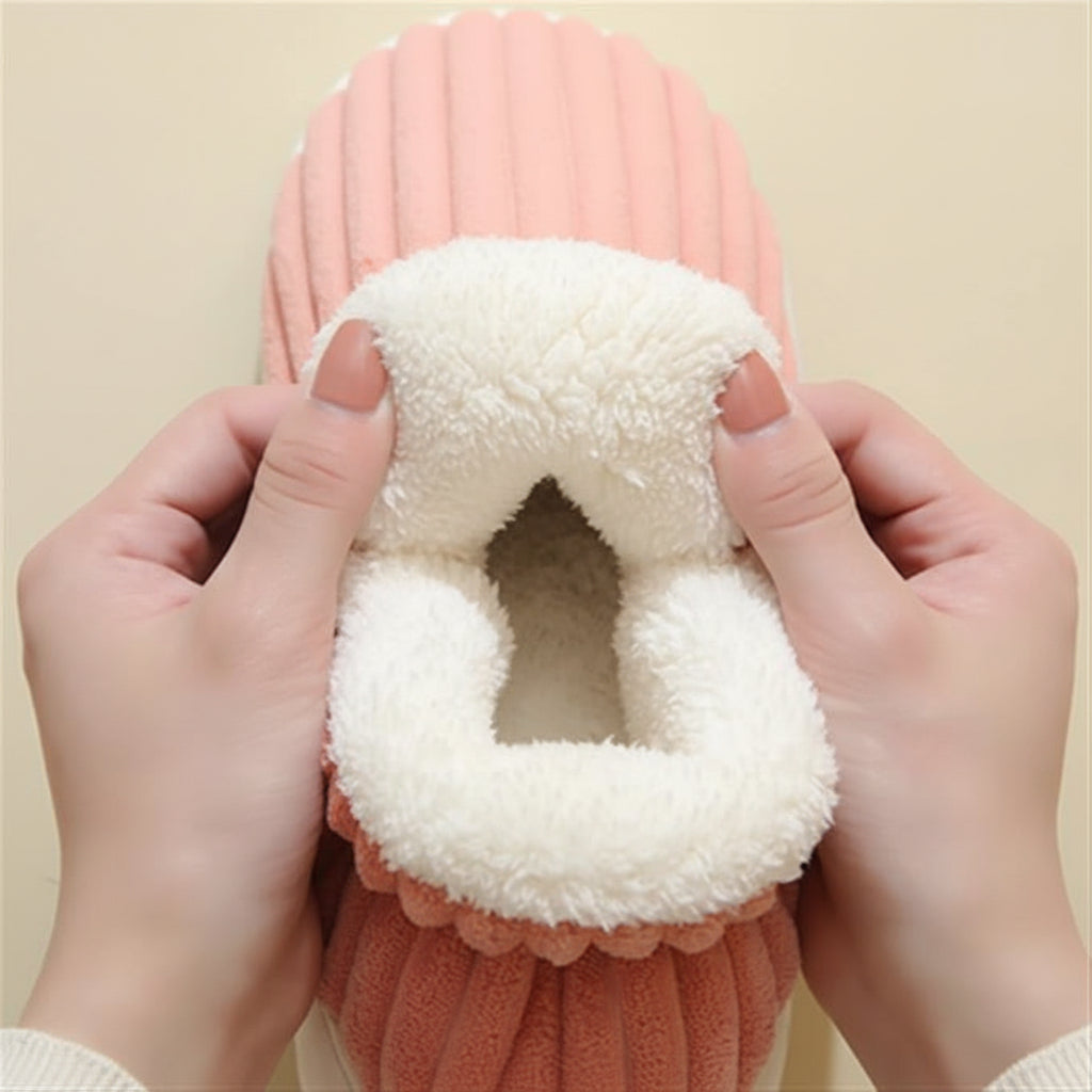 Hands holding open the plush-lined collar of a pink corduroy slipper.