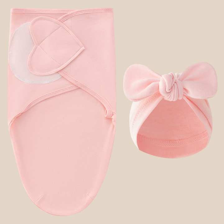 Pink swaddle blanket and matching bow hat displayed against a beige background