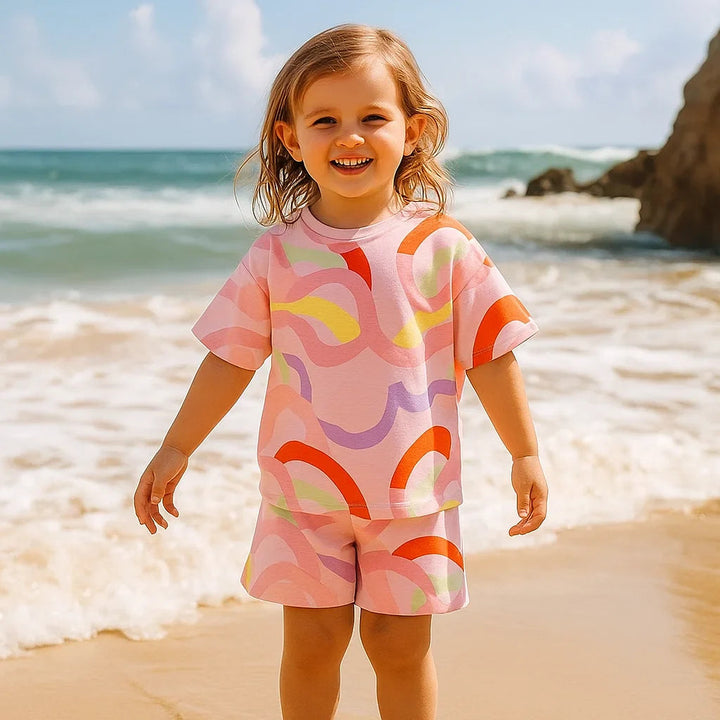 Child wearing a pink swirl-print top and shorts on a sandy beach