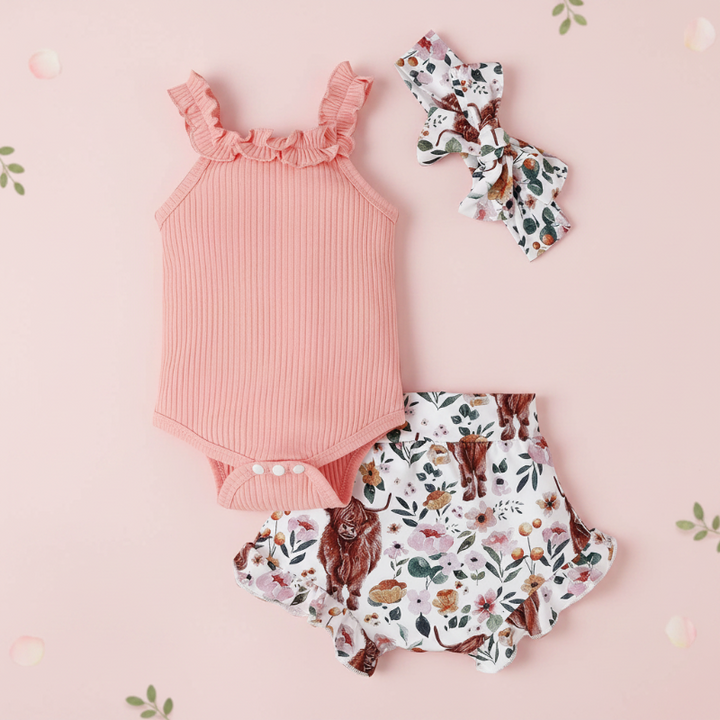 Pink three-piece baby outfit with a snap-bottom romper, printed shorts and bow headband