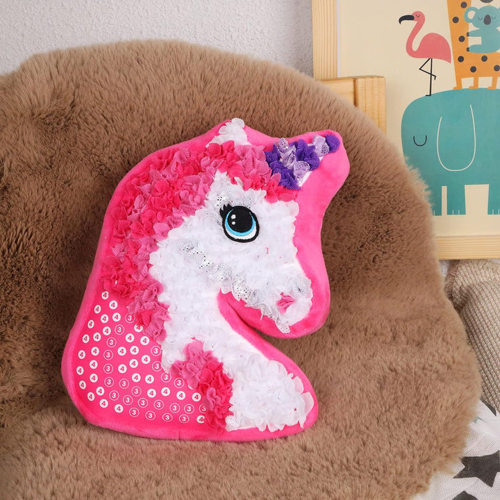 Pink and white unicorn pillow resting on a brown fuzzy chair.