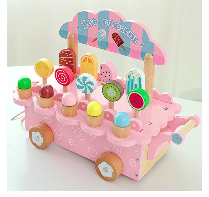 Pink wooden ice cream cart with a striped sign, wooden wheels, and rows of pretend treats