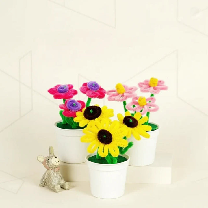 Pink flowers and yellow sunflowers made from fuzzy wire, displayed in white pots