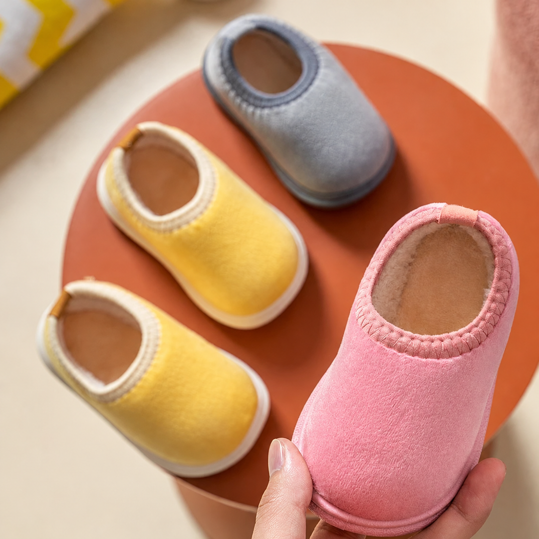 Pink winter slipper held beside yellow and gray slippers with soft linings