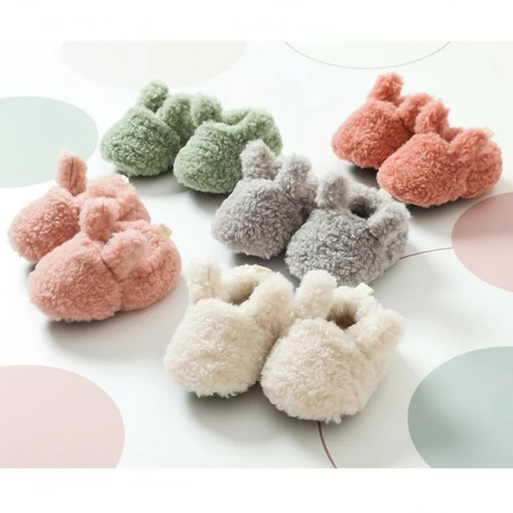 Five pairs of plush baby booties in assorted colors arranged together