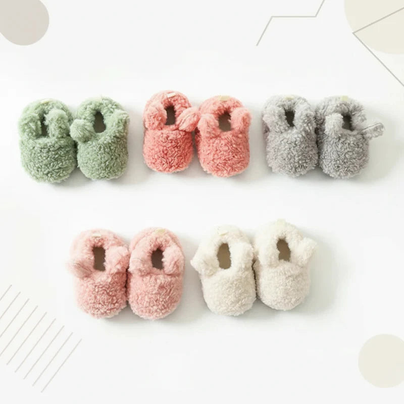 Five pairs of plush baby shoes arranged in two rows