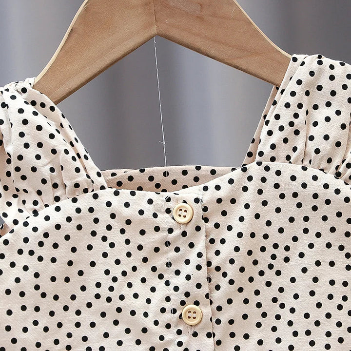 Square neckline and front buttons on the cream and black polka-dot top