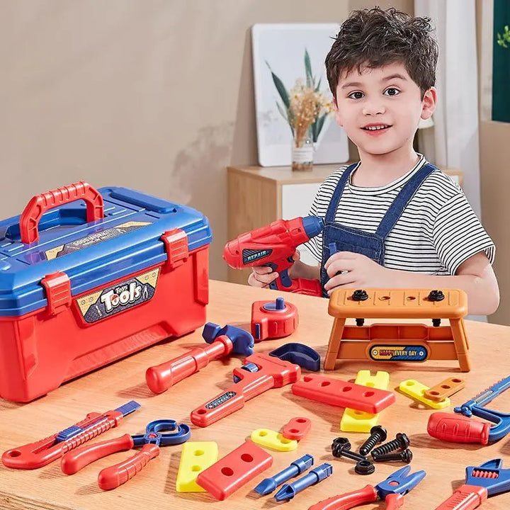 Child holding a red toy drill with a workbench, toolbox, and colorful tool pieces on a table