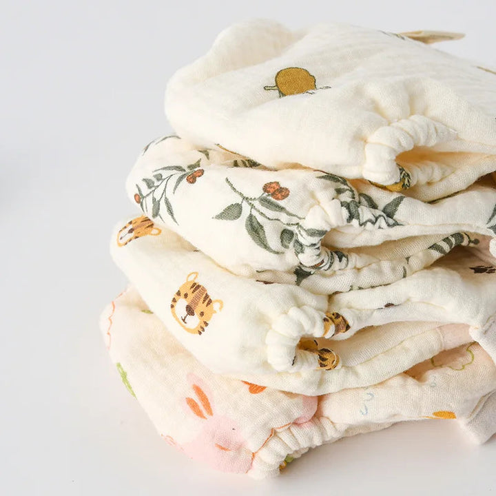 Stack of folded cotton cloth diapers in assorted fruit, leaf, and animal prints