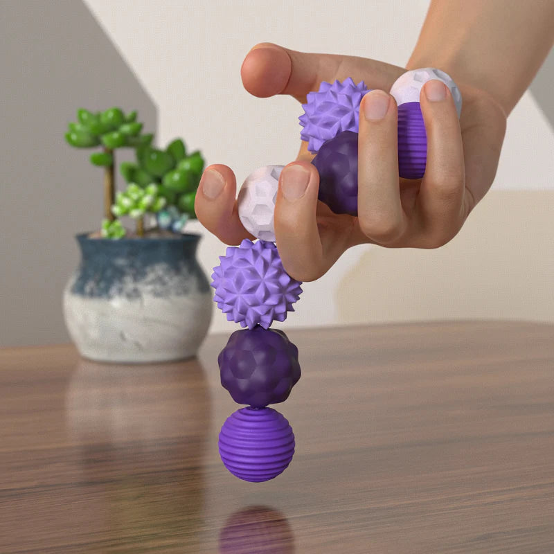 Hand holding connected purple and white magnetic silicone balls above a wooden tabletop