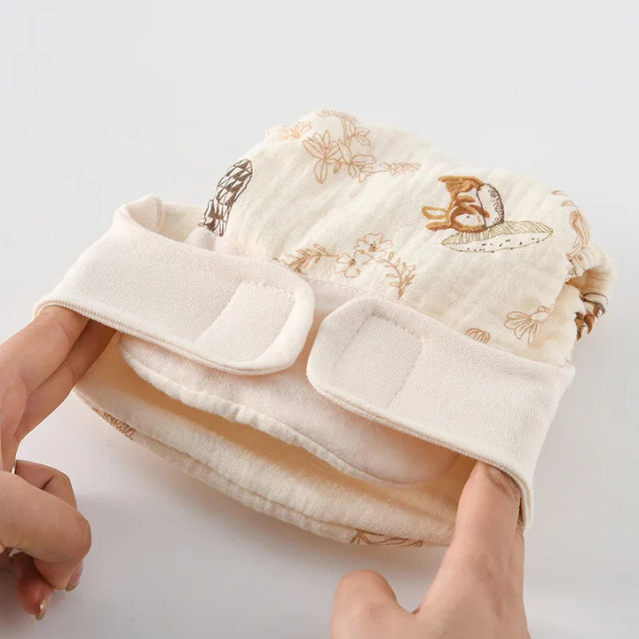 Hands stretch the waistband of a rabbit-print cloth diaper with hook-and-loop tabs