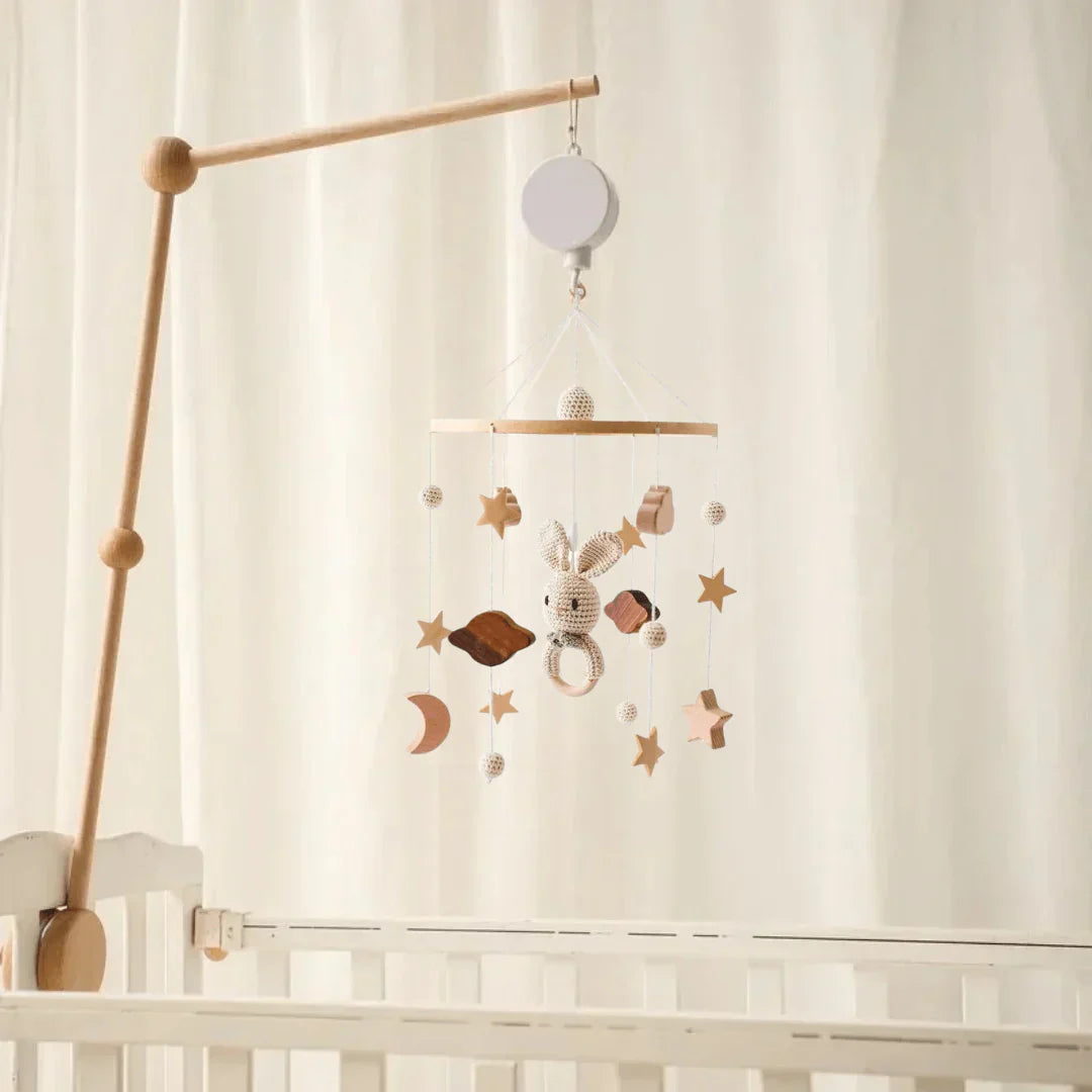 Rabbit-and-star baby mobile suspended from a wooden mounting arm above a white crib