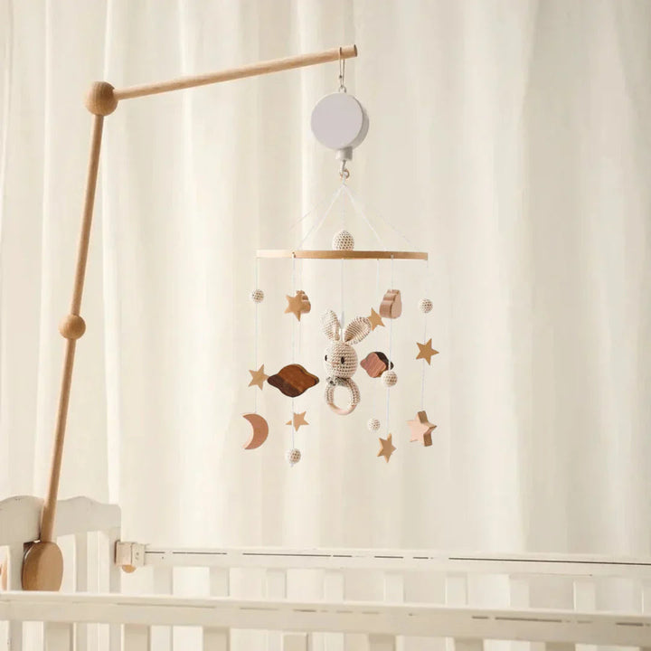 Rabbit-and-star baby mobile suspended from a wooden mounting arm above a white crib