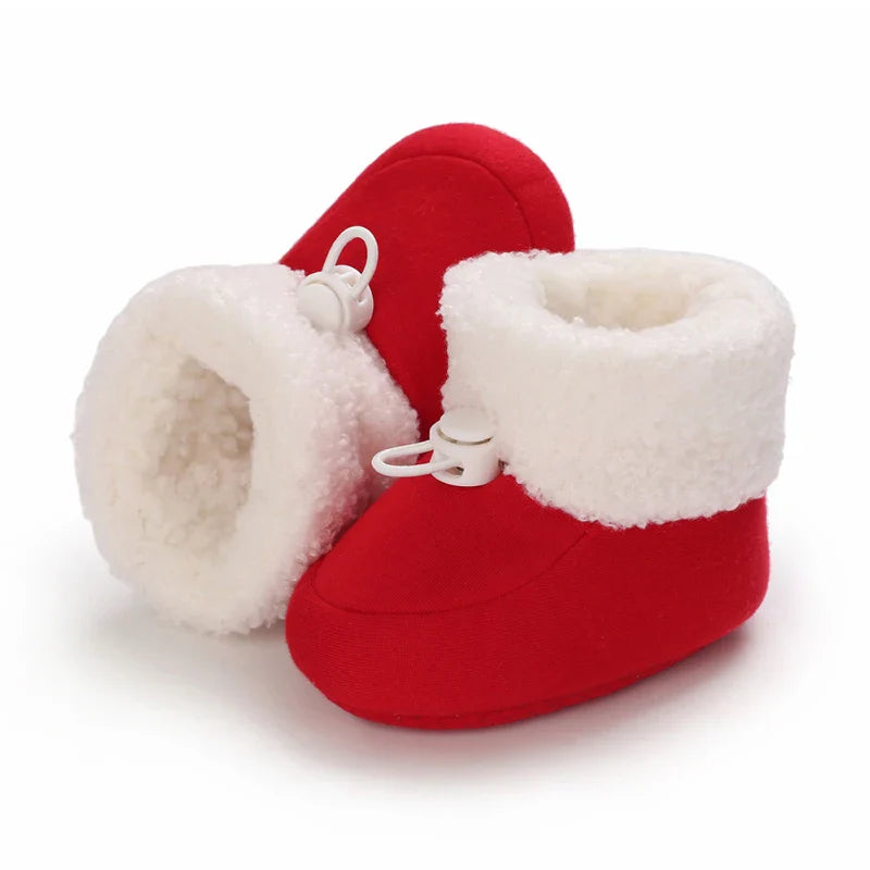 Red baby winter boots with fluffy white cuffs and one boot resting on its side