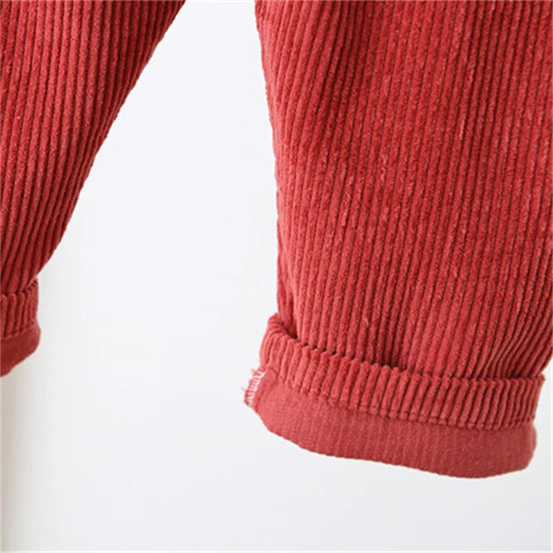 Close-up of rolled leg cuffs on red corduroy overalls