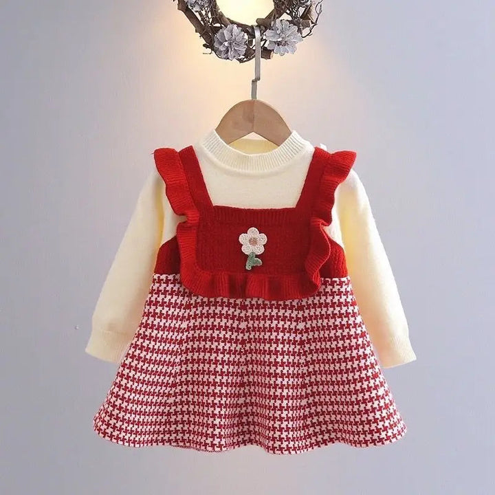 Red dress on a hanger with cream long sleeves and a flower-accented ruffled bodice
