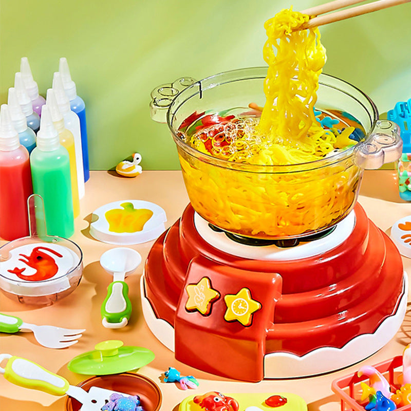 Yellow craft strands lifted over a red toy cooking pot beside color bottles and figure molds