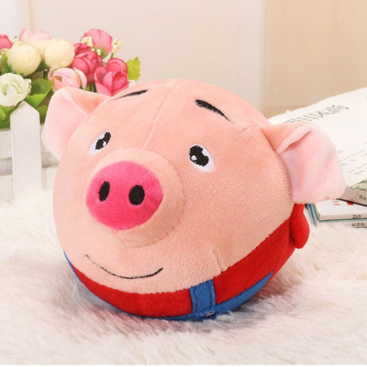 Pink pig toy ball with a red outfit, blue straps, and a smiling face