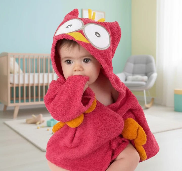 Baby wearing a red owl bathrobe with large eyes on the hood and yellow accents