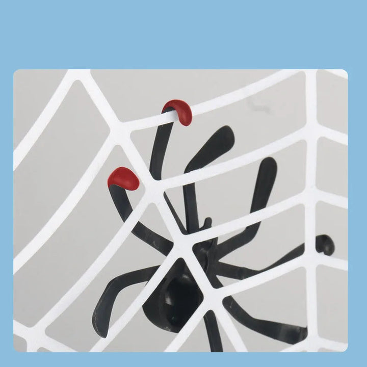 Close-up of a black spider with red-tipped legs against the white web