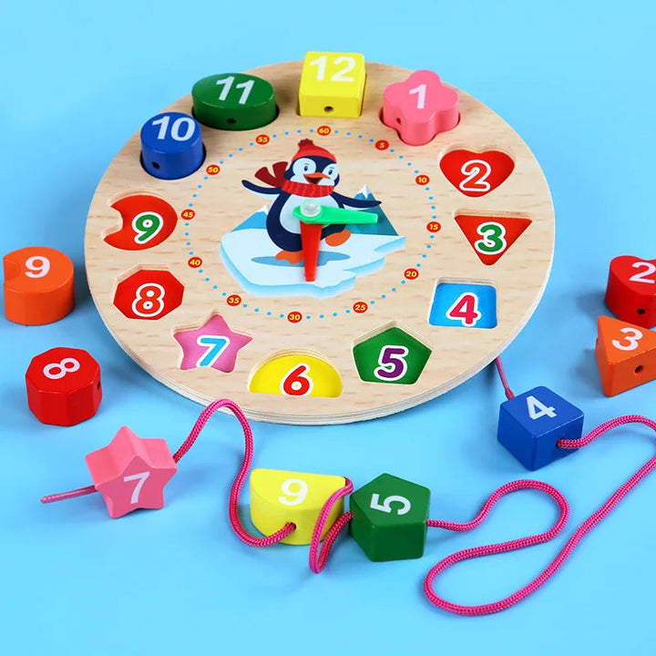 Wooden clock surrounded by removable number blocks, with several blocks threaded onto a pink lace