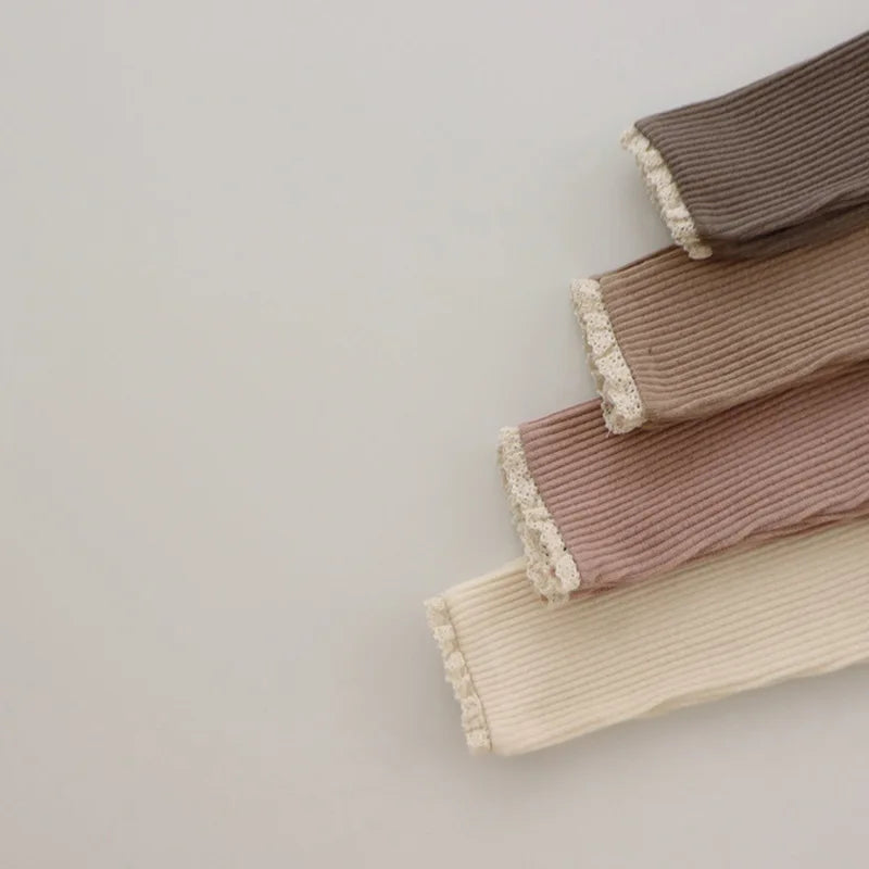Close-up of lace-trimmed cuffs on brown, khaki, pink and beige ribbed leggings.