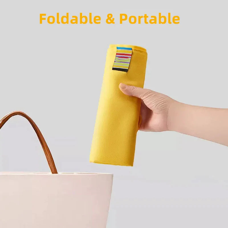 Rolled yellow chair harness held above a tote bag to show its compact folded shape.