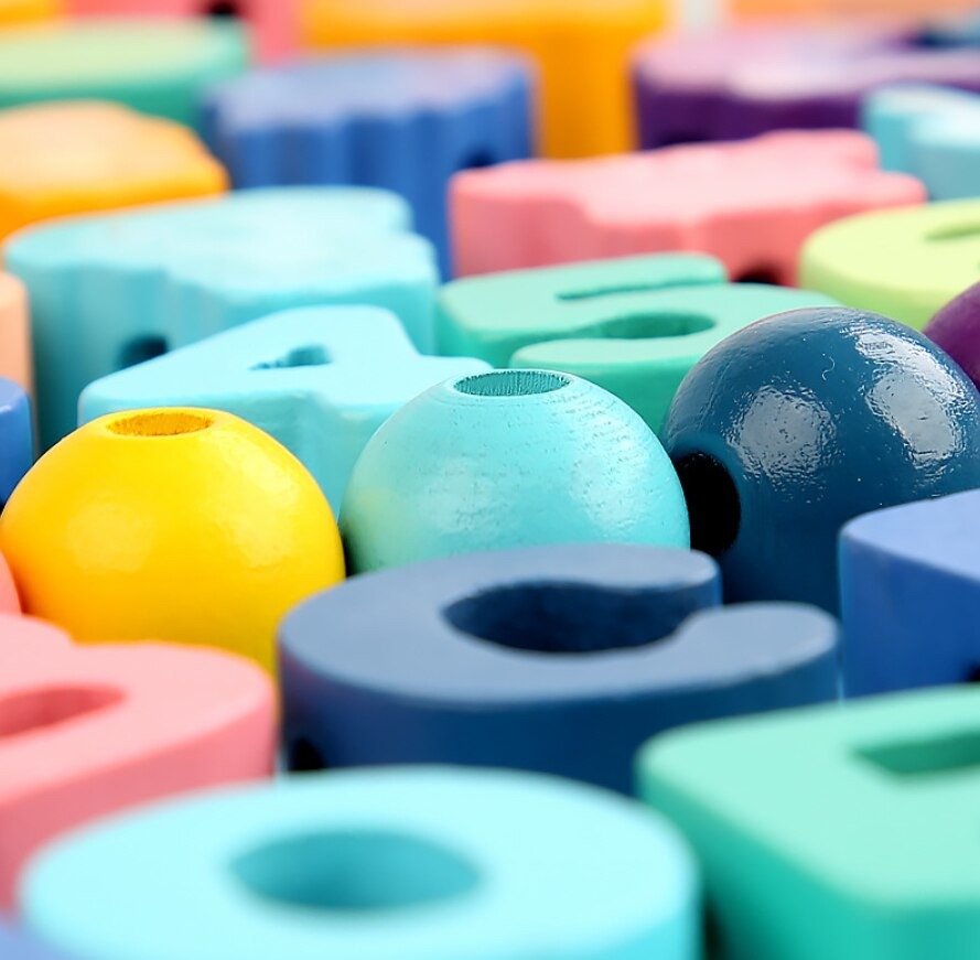 Close-up of colorful round and letter-shaped wooden beads with threading holes