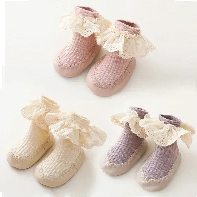 Pink, beige, and purple baby sock shoe pairs with ruffled lace cuffs