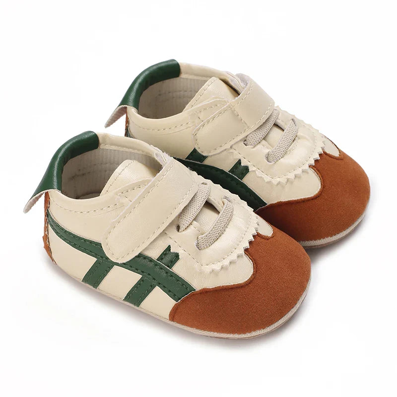 Cream and rust-colored baby sneakers with green side stripes and fastening straps